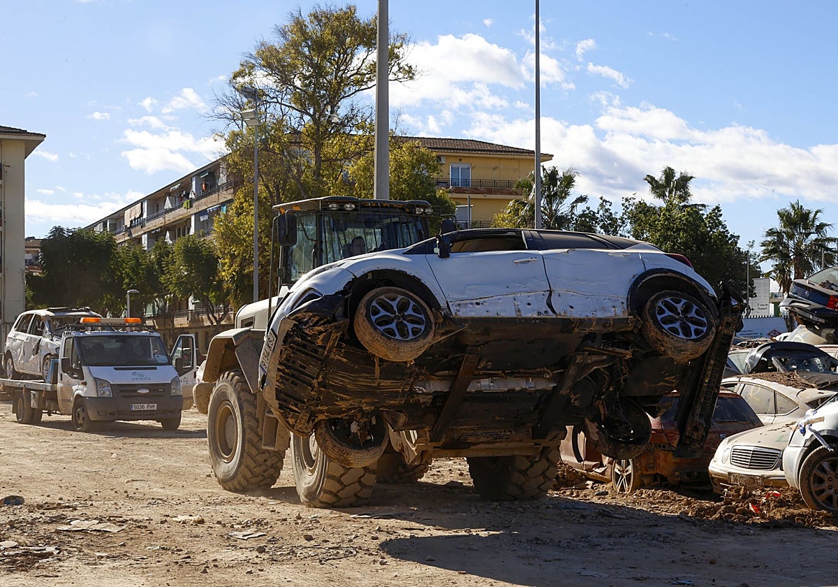 Un tractor transporta un vehículo dañado por la dana en Benetússer.