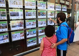 Una pareja consulta los anuncios de una agencia inmobiliaria