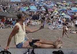 Una turista se fotografía junto a la playa de la Malvarrosa.
