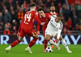 Mbappé conduce el balón ante la oposición de dos jugadores del Liverpool.
