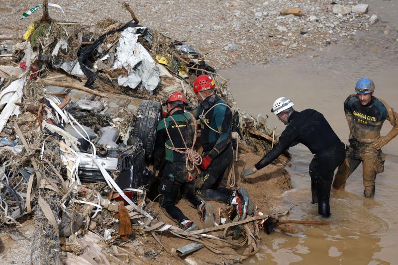 Varios agentes del GEA de la Guardia Civil inspeccionan un vehículo arrastrado por la riada.