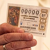 Una persona disfrazada sujeta un décimo de la Lotería de Navidad.