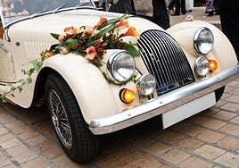 Coche antiguo adornado con un ramo de flores de novia
