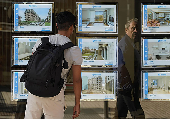 Un joven mira el escaparate de una inmobiliaria.