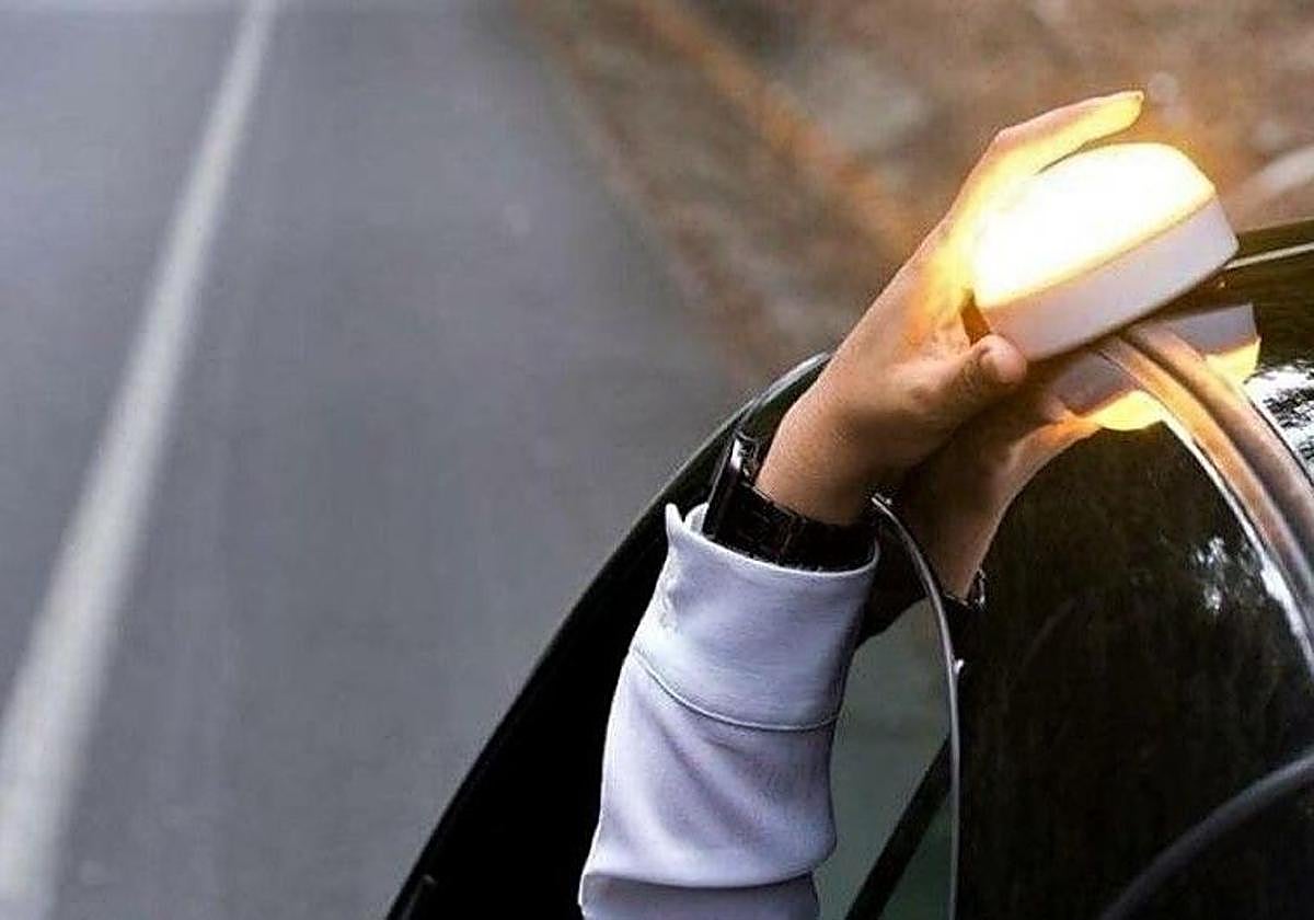 Una persona coloca la báliza V-16 en el coche.