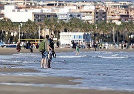 Dos turistas se mojan los pies en la playa de la Malvarrosa este domingo.