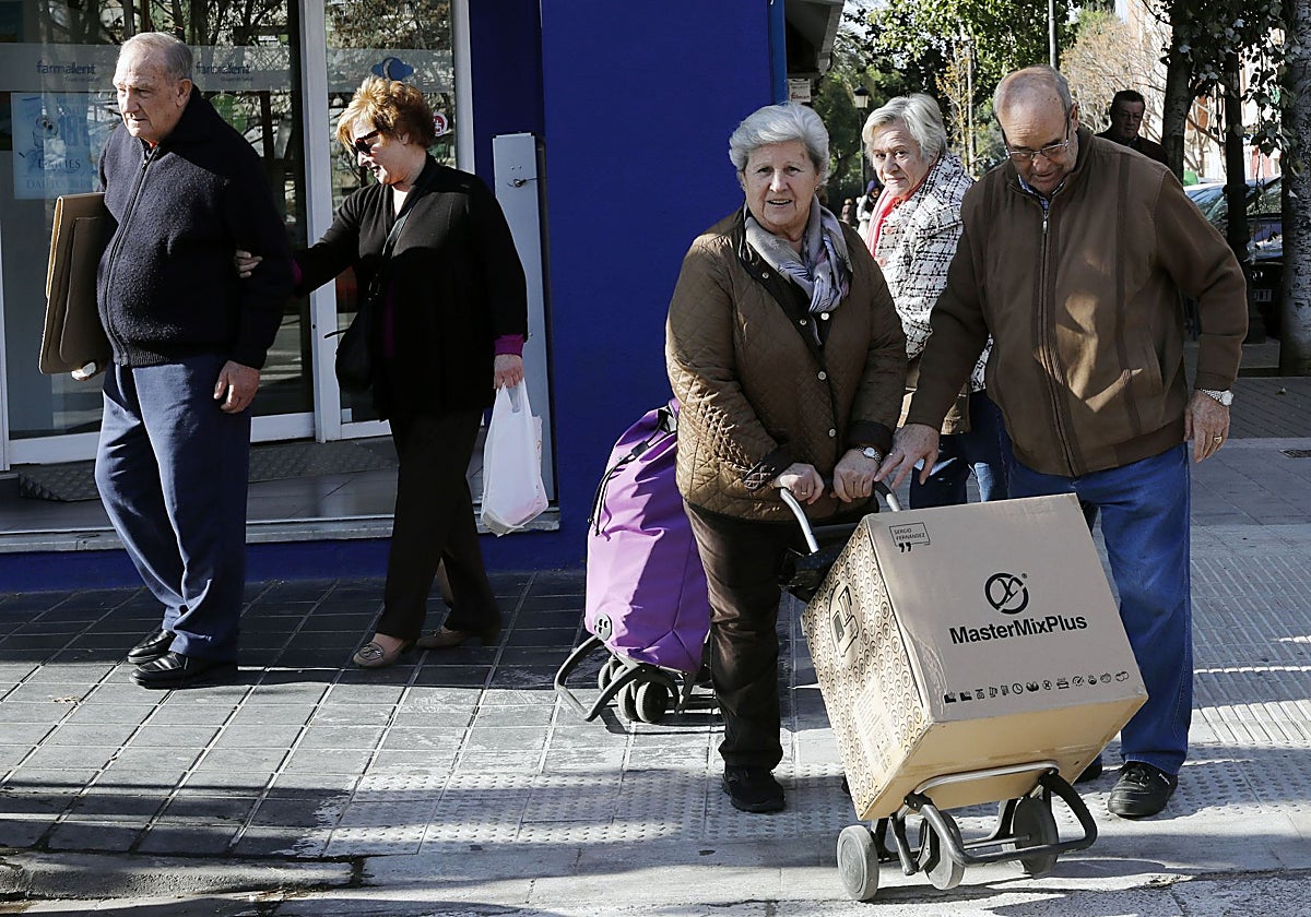 Dos personas mayores cargan una caja, en Valencia, en diciembre de 2019.