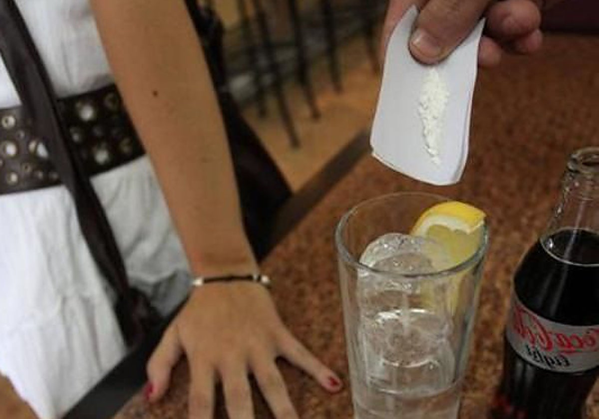 Simulación de un individuo echando droga en una bebida.