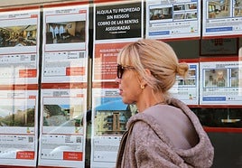 Una mujer pasa frente a una inmobiliaria con viviendas en alquiler.