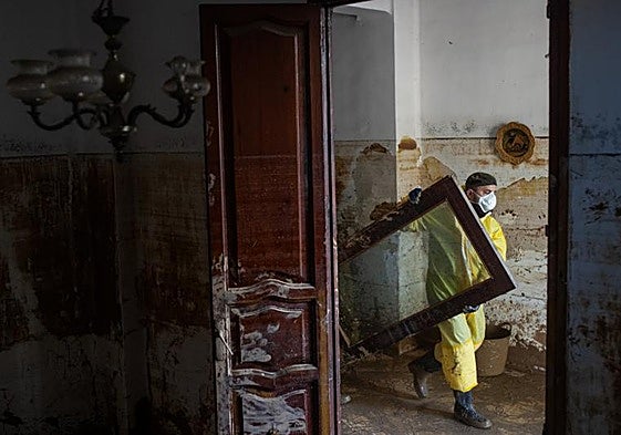 Un voluntario retira un mueble destrozado por la dana en los días posteiores a la tragedia.