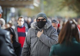 Un hombre se abriga del frío por la calle.
