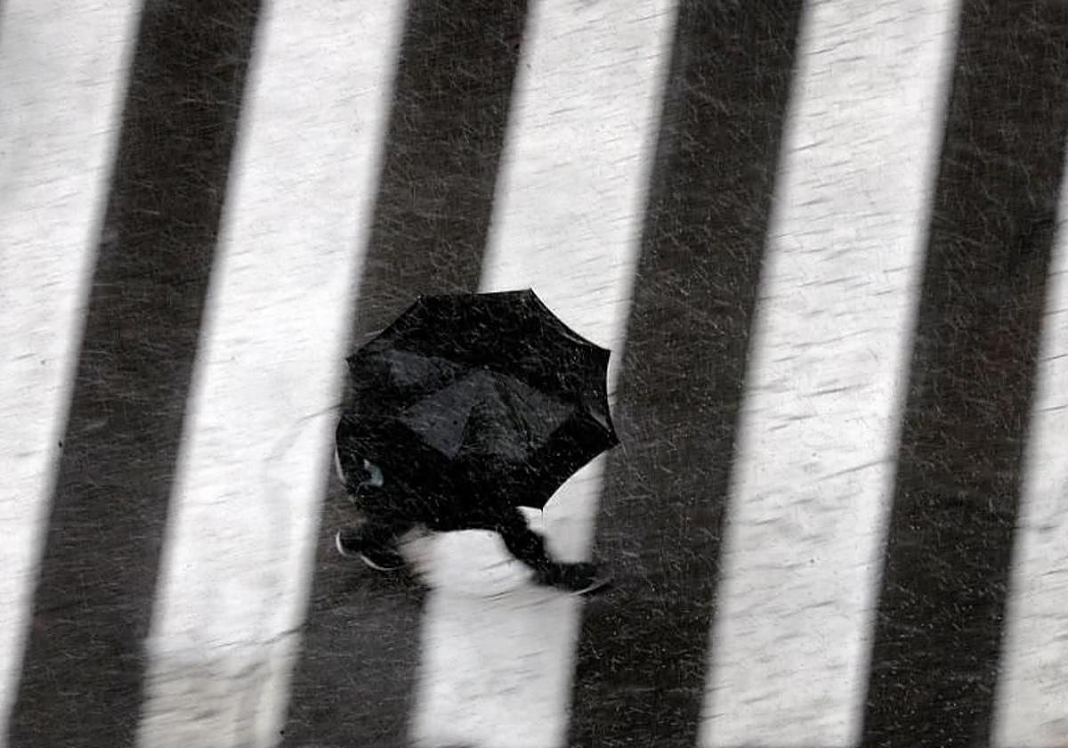 Un hombre pasea bajo la lluvia en Valencia.