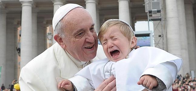 El Papa Francisco coge en brazos a un niño vestido de pontífice. / Efe