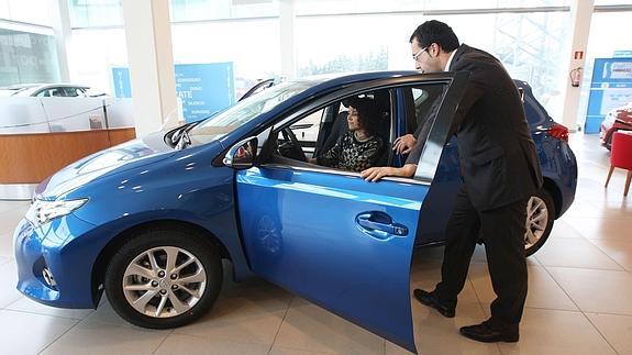 Un empleado muestra un coche en un concesionario. 