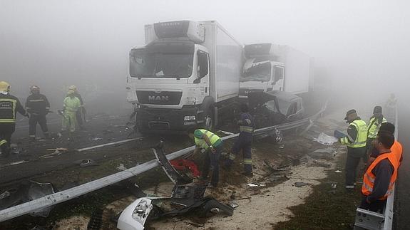 Efectivos de los servicios de emergencia y la policía junto a dos de los camiones implicados en un accidente múltiple de unos 50 vehículos producido en Lugo. 