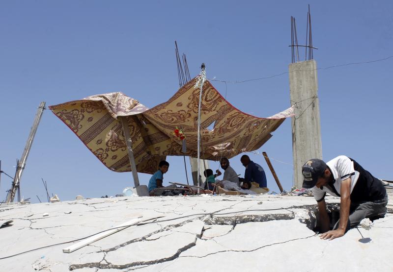 Un grupo de palestinos descansan en las ruinas en Gaza