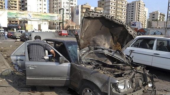 Un policía inspecciona varios coches destrozados tras una explosión 