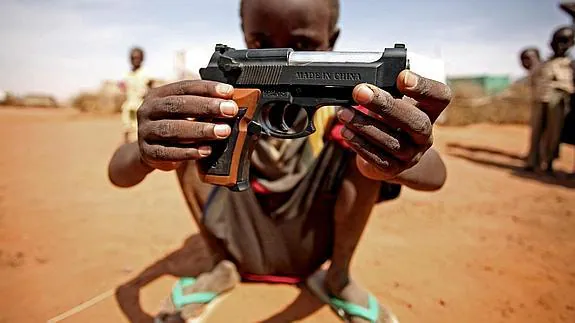 Un niño sudanés del campo de desplazados de El Fasher sostiene una pistola de juguete.