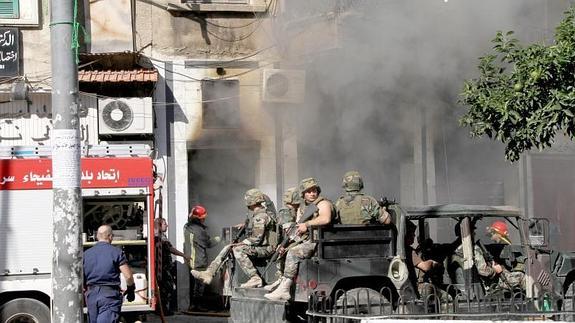 Una casa se quema detrás de miembros del Ejército libanés 