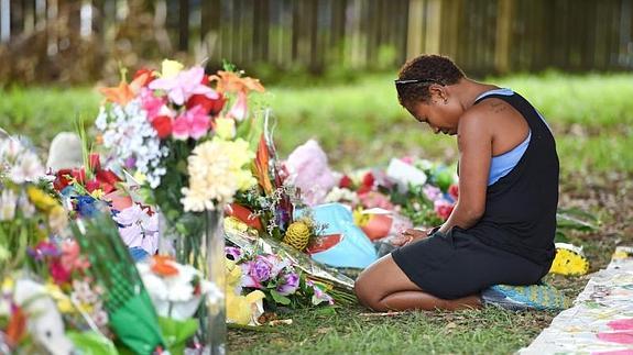 Una mujer reza ante la ofrenda floral en homenaje a las víctimas. 