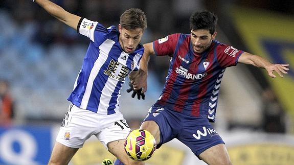 El centrocampista de la Real Sociedad Sergio Canales (i) disputa un balón con Eneko Bóveda, del Eibar.