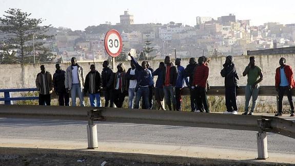 Inmigrantes en la carretera de acceso al paso fronterizo, situada junto al CETI. 