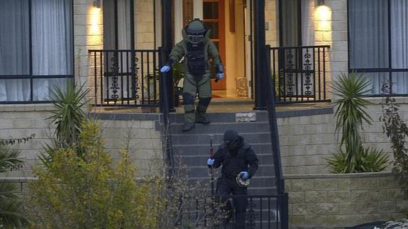 Dos artificieros con trajes de protección participan en el registro de la vivienda en Greenvale. 