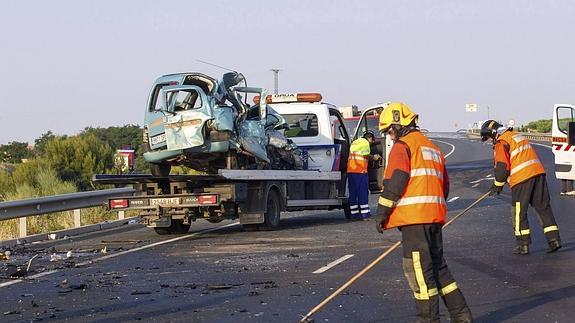 Bomberos limpian la carretera de los restos de un accidente.