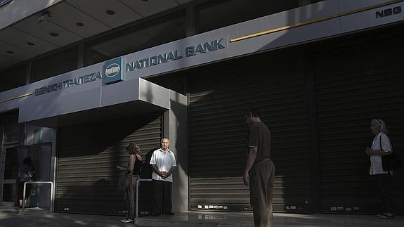 Ciudadanos griegos esperan la apertura de un banco en Atenas.