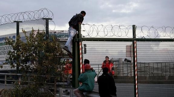 Un inmigrante salta una cerca antes de intentar tomar un tren en su ruta hacia Inglaterra, en Calais.