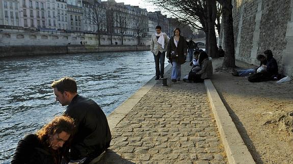 Varios jóvenes toman el sol en la ribera del Sena, en París.