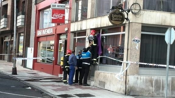 Los bomberos, ayudados por la Policía Local, tratan de acceder al bar.