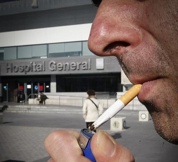 Un hombre enciende un pitillo a las puertas del madrileño hospital de La Paz.