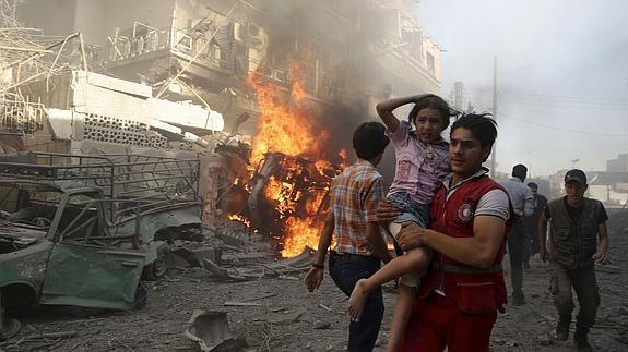 Un miembro de la Media Luna Roja traslada a una niña tras un bombardeo del régimen sirio.