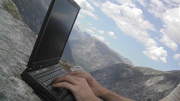 Una persona utiliza un portátil en pleno paisaje montañoso.