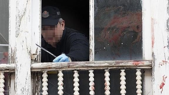 Un agente inspecciona la ventana por la que fue arrojada la niña. 