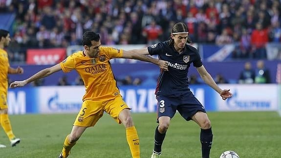 El defensa brasileño del Atlético de Madrid Filipe Luis (d) lucha el balón con Sergio Busquets, del FC Barcelona.