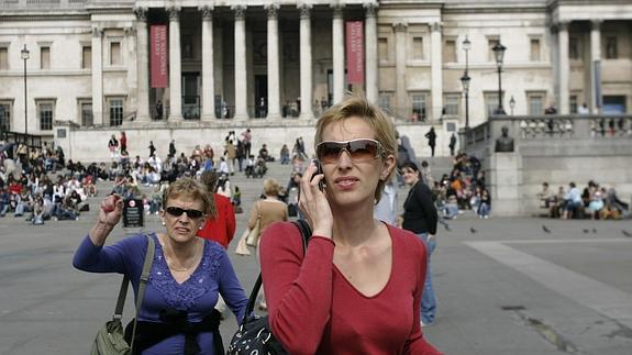 Una turista habla por un teléfono móvil mientras visita Trafalgar Square, en Londres.