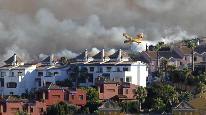 Un helicóptero del Infoca, durante la extinción del incendio, muy próximo a las urbanizaciones. 