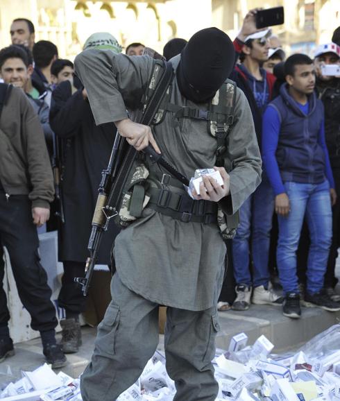Un miembro del Daesh se dispone a prender fuego a paquetes de cigarrillos norteamericanos confiscados en Raqa. 