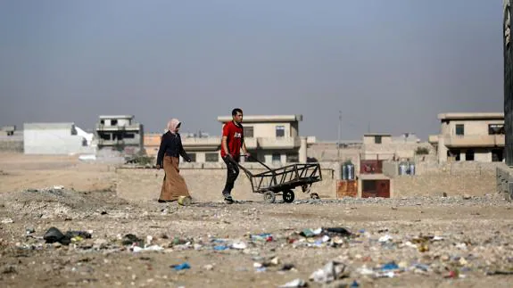 Dos personas caminan en un descampado del noreste de Mosul.