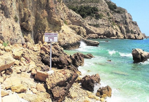 El cartel instalado en la cala del Tangó en el que se prohibe el paso debido a los desprendimientos de rocas. 