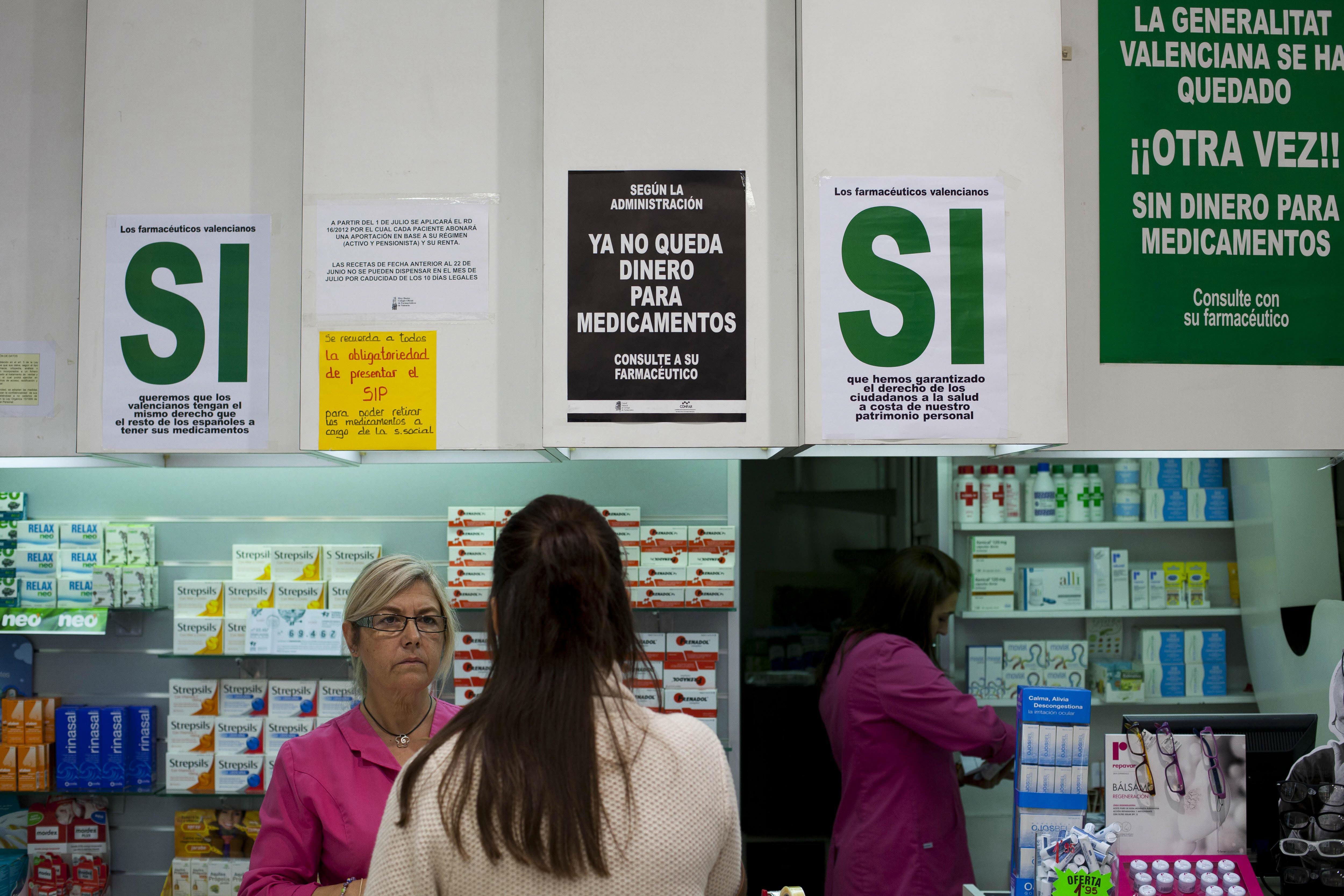 Una dependienta atiende a una joven en una farmacia de Valencia.