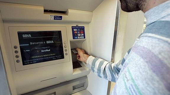 Un joven sacando dinero con su tarjeta de crédito.