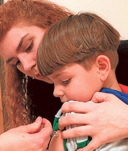 Una madre sujeta a su hijo mientras le administran una vacuna.