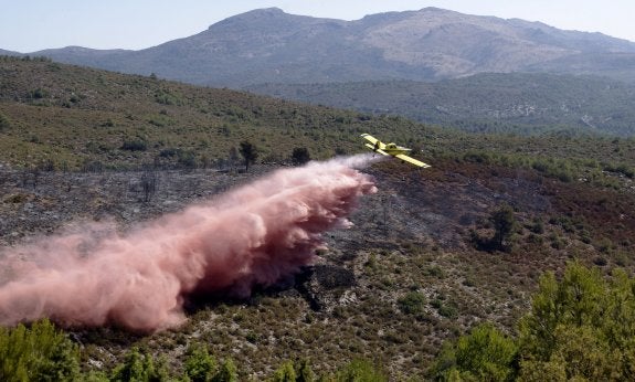 Un hidroavión realiza una descarga en la zona del incendio. :: efe