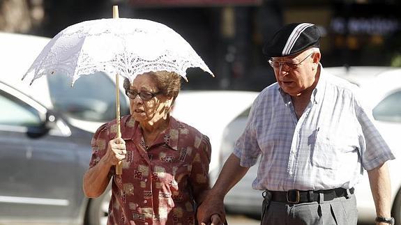 Una mujer se proteje del sol con una sombrilla esta mañana en Valencia