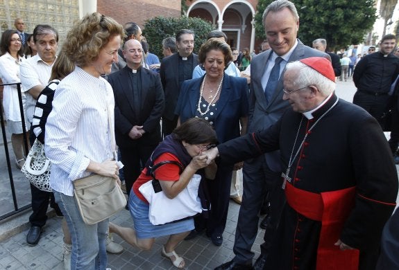 El cardenal arzobispo de Valencia saludado por varias mujeres ante la mirada de las autoridades a su llegada a la ciudad. :: jesús signes