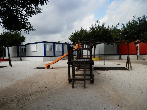 La zona de juegos y detrás los barracones que forman las nueve aulas a las que asisten desde el año 2008 los alumnos del colegio de La Xara. :: CONCHA PASTOR
