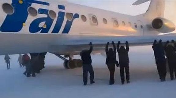 Pasajeros empujan un avión para despegar en Siberia